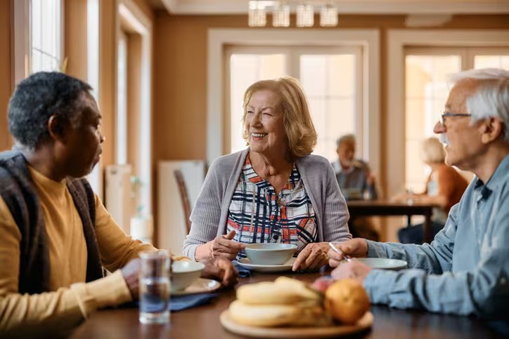 Older adults sharing a meal and friendly conversation around a dining table